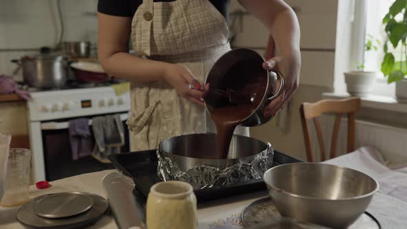 woman pouring biscuit dough into a baking dish close-up alt