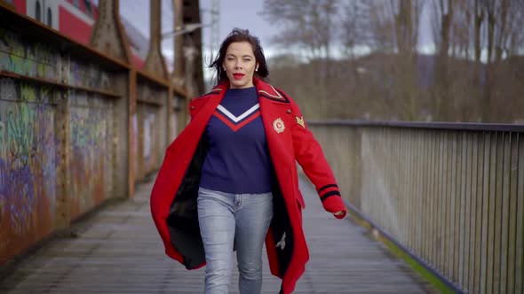 a Brunette with Bright Lipstick and a Piercing on Her Face Is Walking on a Railway Bridge. She's alt