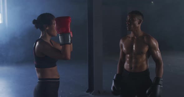 African american man and woman wearing boxing gloves training throwing punches in empty room alt