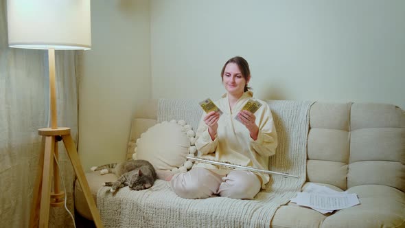 Happy woman musician with money in euro at home on sofa in living room