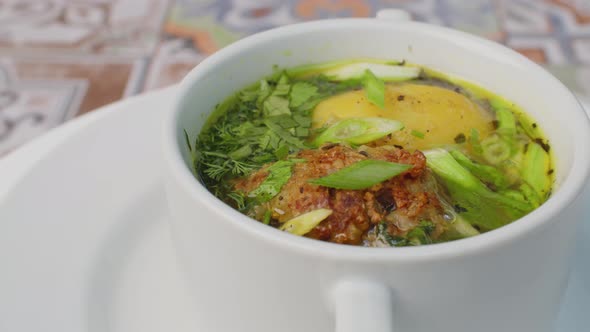 Chicken Soup with Potato and Herbs Spinning Round on Table