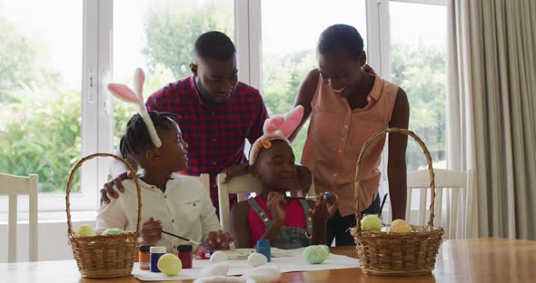 African american family painting easter eggs together at home alt
