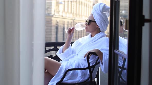 Young Blonde Woman with Glass of Champagne in Bathrobe