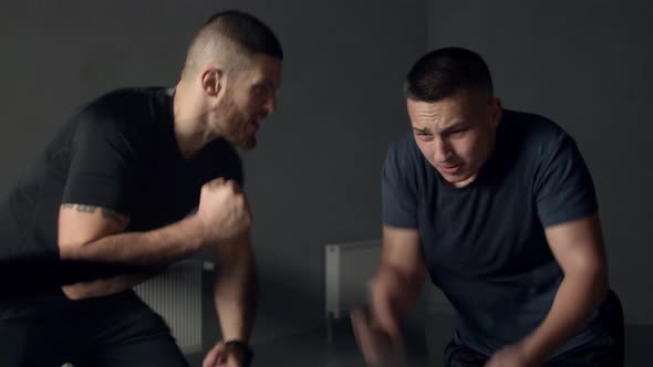 Young Man with Instructor Using Battle Ropes in Gym