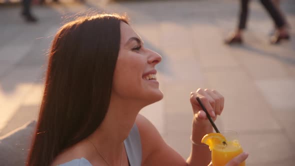 Pretty young woman drinking orange juice at the street cafe