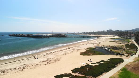 Aerial shot pulling back looking out at sail boats in the harbor of dark blue Pacific Ocean next to alt