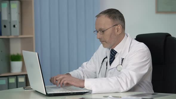 Tired Therapist Filling in Electronic Record Files After Patient Examination alt