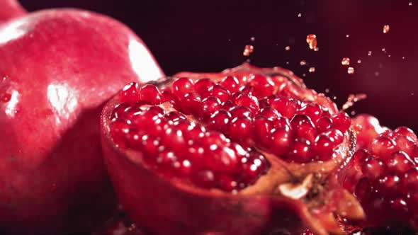 Slow Motion Shot of Pomegranate Juice Splashing Through Pomegranate alt