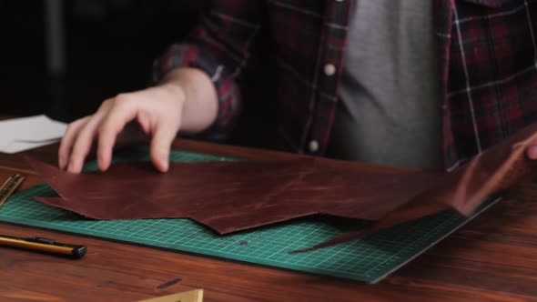 Man Tailor Cutting Artificial Leather with Ruler Closeup alt