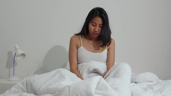 Asian young woman shocked as he wake up late for an appointment on bed in bedroom at home. alt