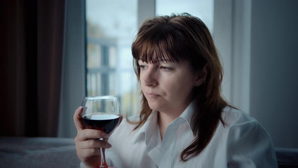 Sad Woman Sitting at Home with a Glass of Wine and Thinking Woman Contemplating Future Plans