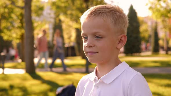 Closeup of a Little Boy Putting on Sunglasses in the Park alt