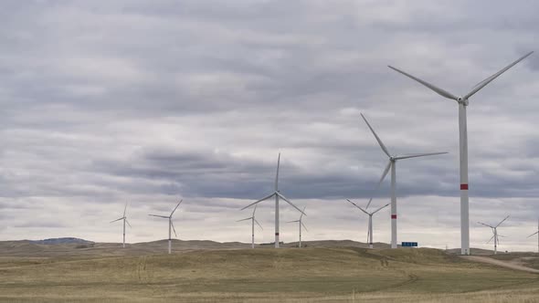 Motion the Blades of a Large Wind Turbine in a Field Against a Background of Cloudy Grey Sky on the alt