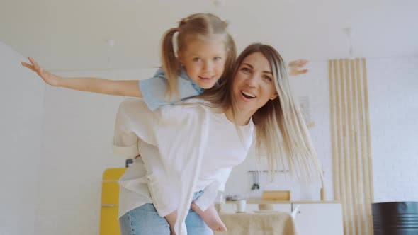 Little Girl Daughter Sitting on Back of Her Mother