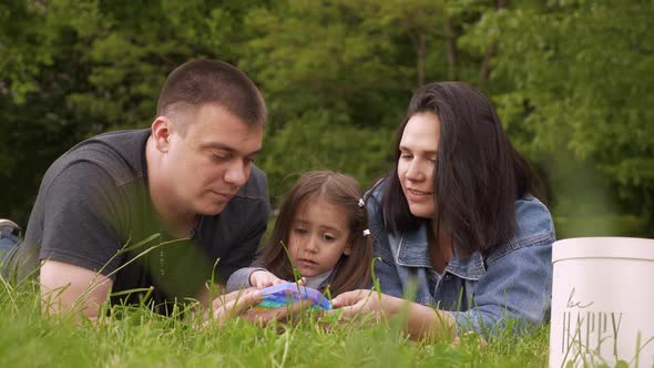 Mom Dad and Baby in Nature Playing with a Toy Pop It alt