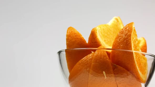 Slices Of Orange In A Glass Plate Are Spinning On A White Background