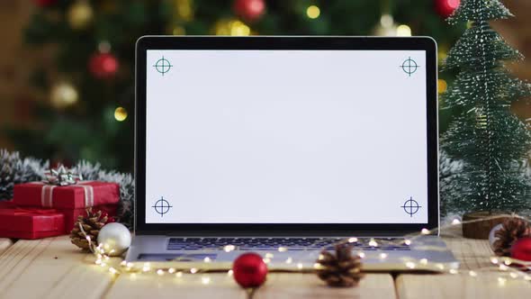 Video of wooden table with christmas decorations and laptop over christmas tree alt