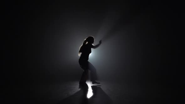 Lady Practicing Capoeira in Darkness Against Spotlight in Studio. Slow Motion. alt