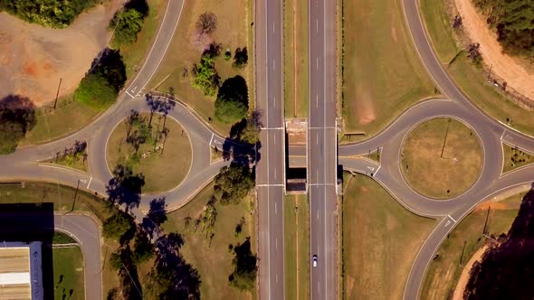 Aerial of highway interchange with roundabouts. Red car drives left to right alt