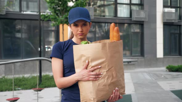 Portrait Serious Food Delivery Woman Courier Holds Paper Bag with Groceries alt