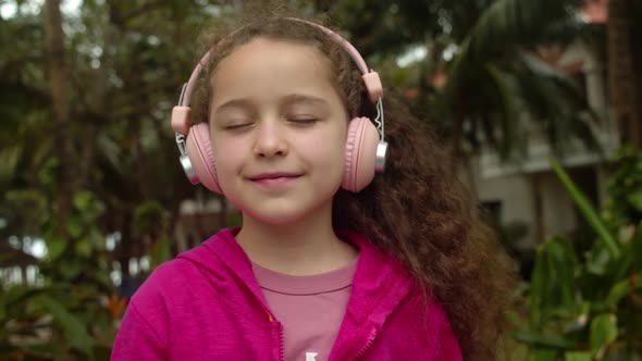 Portrait of Cute Little Girl With Headphones Listening To Music alt