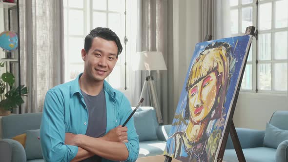 Asian Artist Man Holding Paintbrush Wipe The Sweat Before Crossing His Arms And Smiling After Finish alt