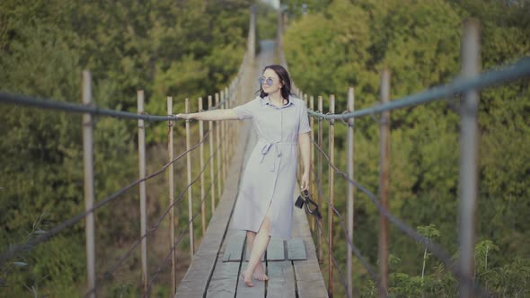 Woman in a Beautiful Dress, Standing on a Bridge in Woods alt