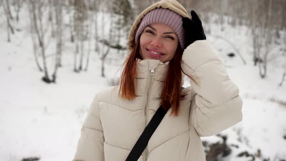 A Young Girl Traveler in Warm Winter Clothes Stands in the Winter Forest