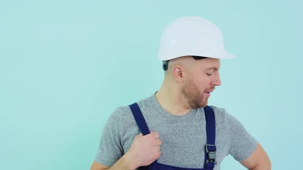 General Worker in a Helmet and Overalls Yawns on a Blue Background alt