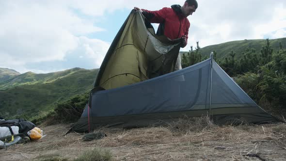 Tourist Traveler Sets Up a Single Tent in the Mountains. Hiking. Solo Tourism alt