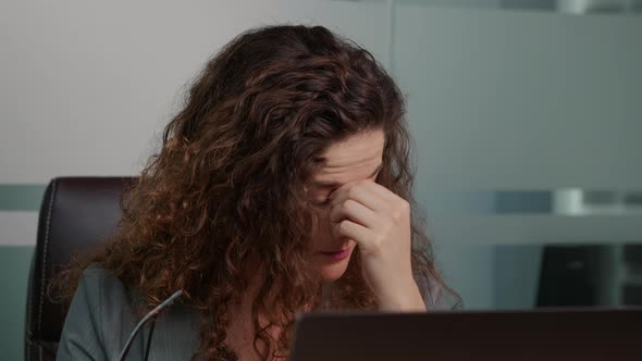 Portrait of tired woman worker taking off glasses and massaging nose and continuies working on. alt