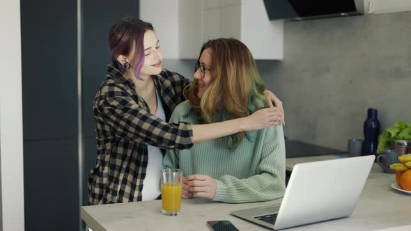 Pregnant Lesbian Woman Embracing Her Partner on Kitchen alt
