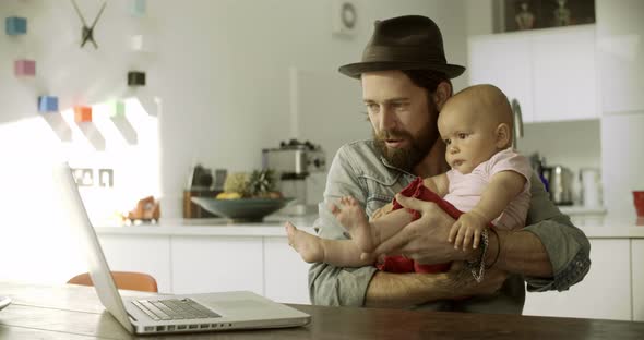 Father and daughter playing with laptop in kitchen