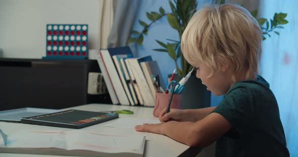 Cute Child Boy Drawing with Pencil Sitting at the Table on Christmas Holidays alt