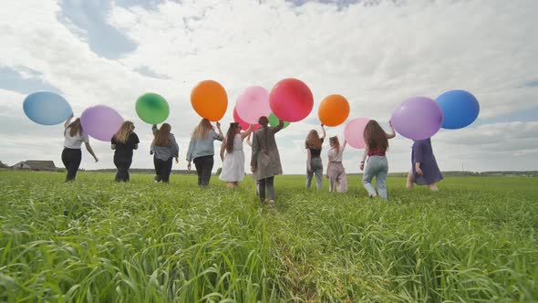 Girls Friends are Walking Across the Field with Large Balloons and Colorful Balloons alt