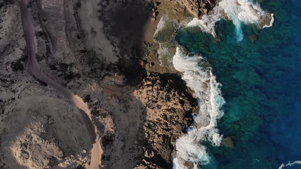 Rocky coast near Porto dos Frades on Porto Santo island, Madeira. Aerial forward top down alt