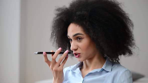 A Young Biracial Woman is Recording Voice Message on a Smartphone alt