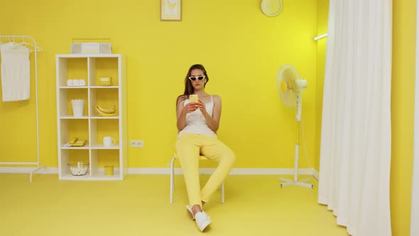 Young Woman Is Using Mobile Phone In Yellow Office