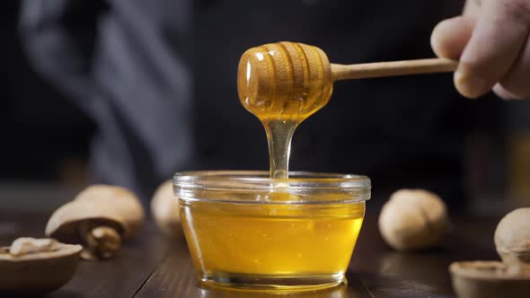 Chef Dips Wooden Honey Stick To the Glass Bowl with Liquid Honey, Cooking with Honey, Sweet Meals alt