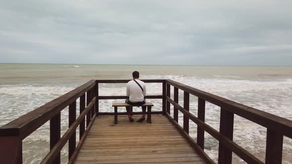 A Man Sits on a Bench and Looks at the Storm alt