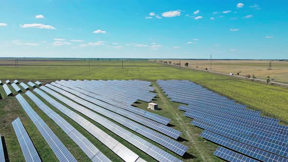 Aerial View of Solar Panels Farm on Green Field Under Blue Sky alt