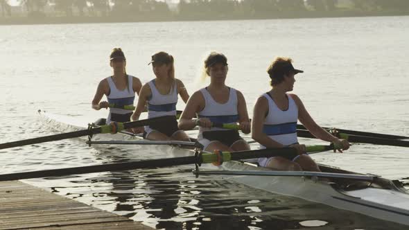 Female rowing team training on a river alt