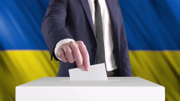 Voting. Man Putting a Ballot into a Voting Box with Ukrainian Flag on Background.