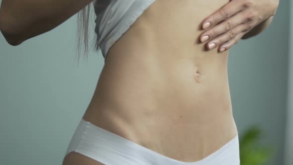 Girl in Front of Mirror Pulling T-Shirt up To Look at Belly, Pulling It in Upset alt