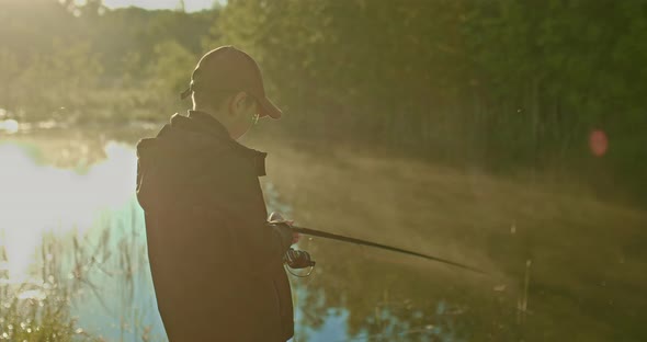 Little Boy is Fishing Alone on Coast of Beautiful Forest Lake in Summer Morning  Prores alt