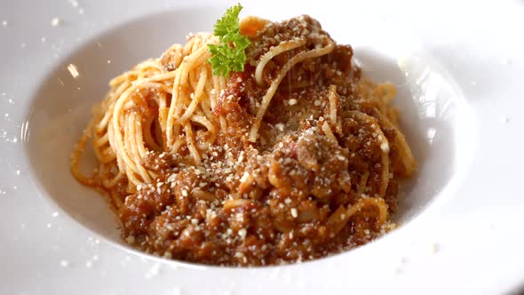 Chef Sprinkles Parmesan on Pasta Bolognese on White Plate in Restaurant alt