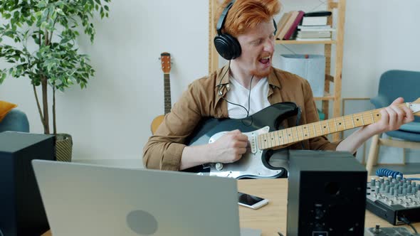 Slow Motion of Attractive Young Musician Playing Guitar and Singing Having Fun in Apartment alt