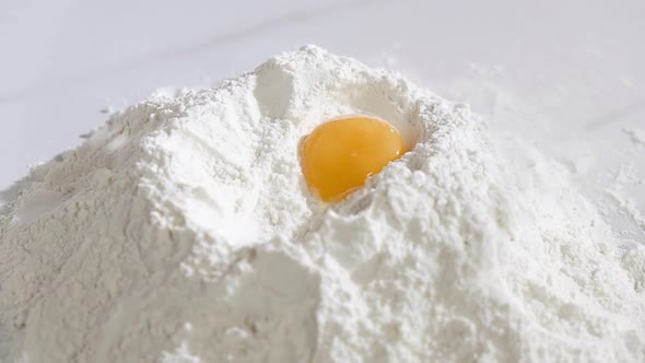 Baker works in kitchen of bakery shop.  chicken egg yolk falls into the flour.