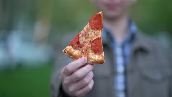 Teen Shows a Slice of Pizza to the Camera
