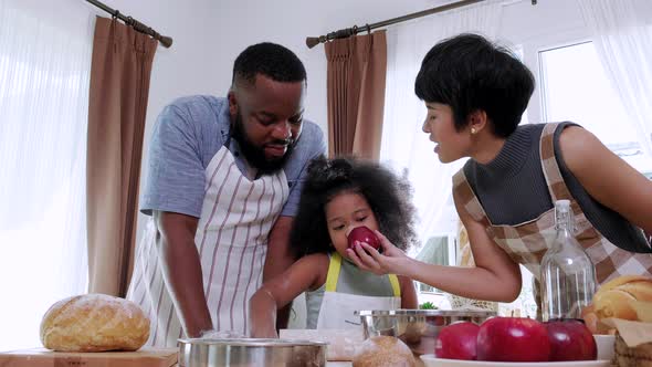 Black father, mom and little daughter cooking at the home kitchen table
